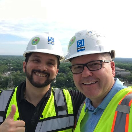 2 men smiling with construction helmets