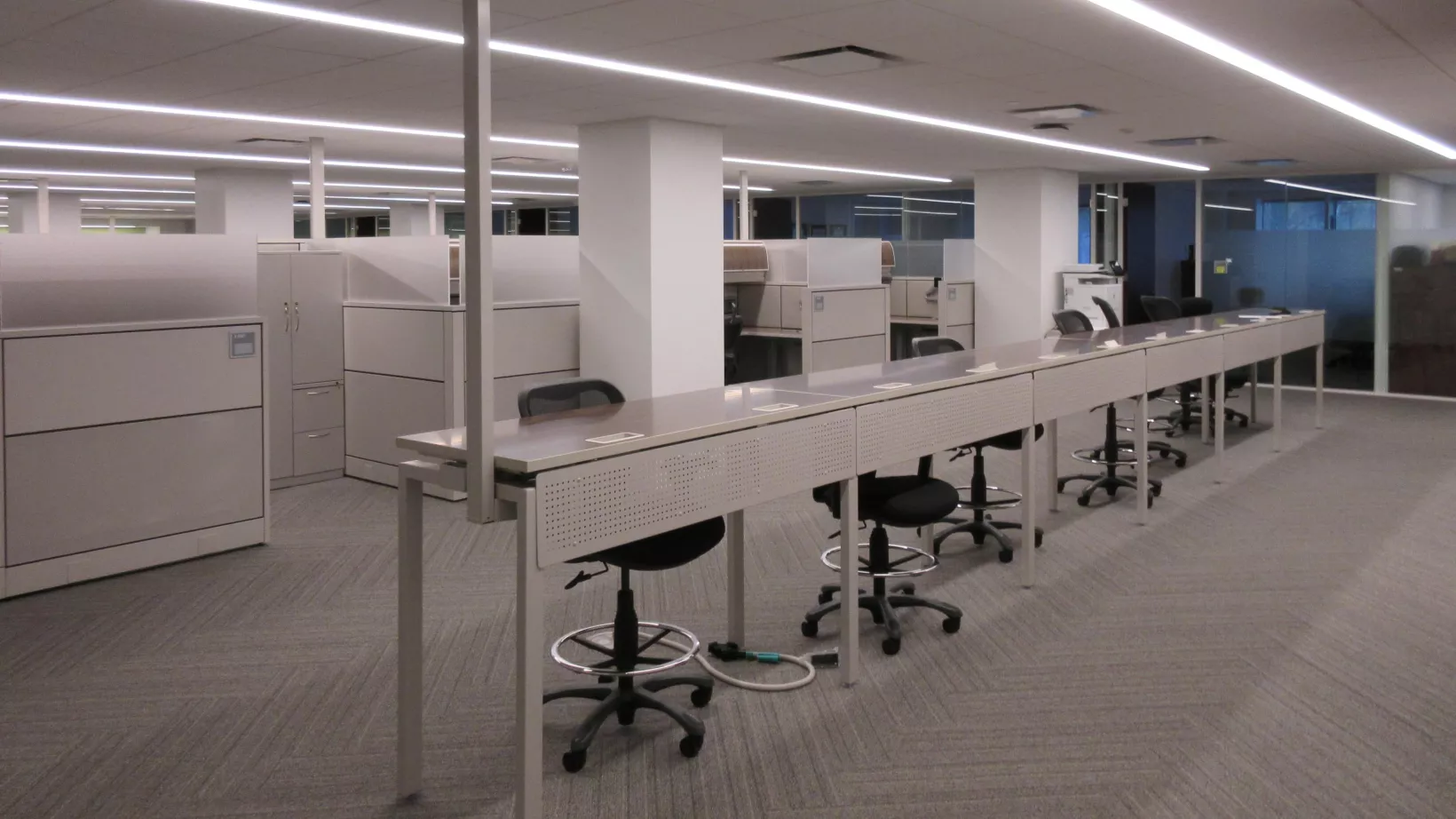 Open work space with desks and chairs, and an overhead fluorescent light