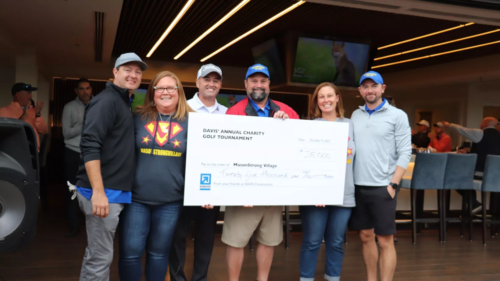 A group of people holding a large check, made out to Mason Strong Village - a nonprofit organization.