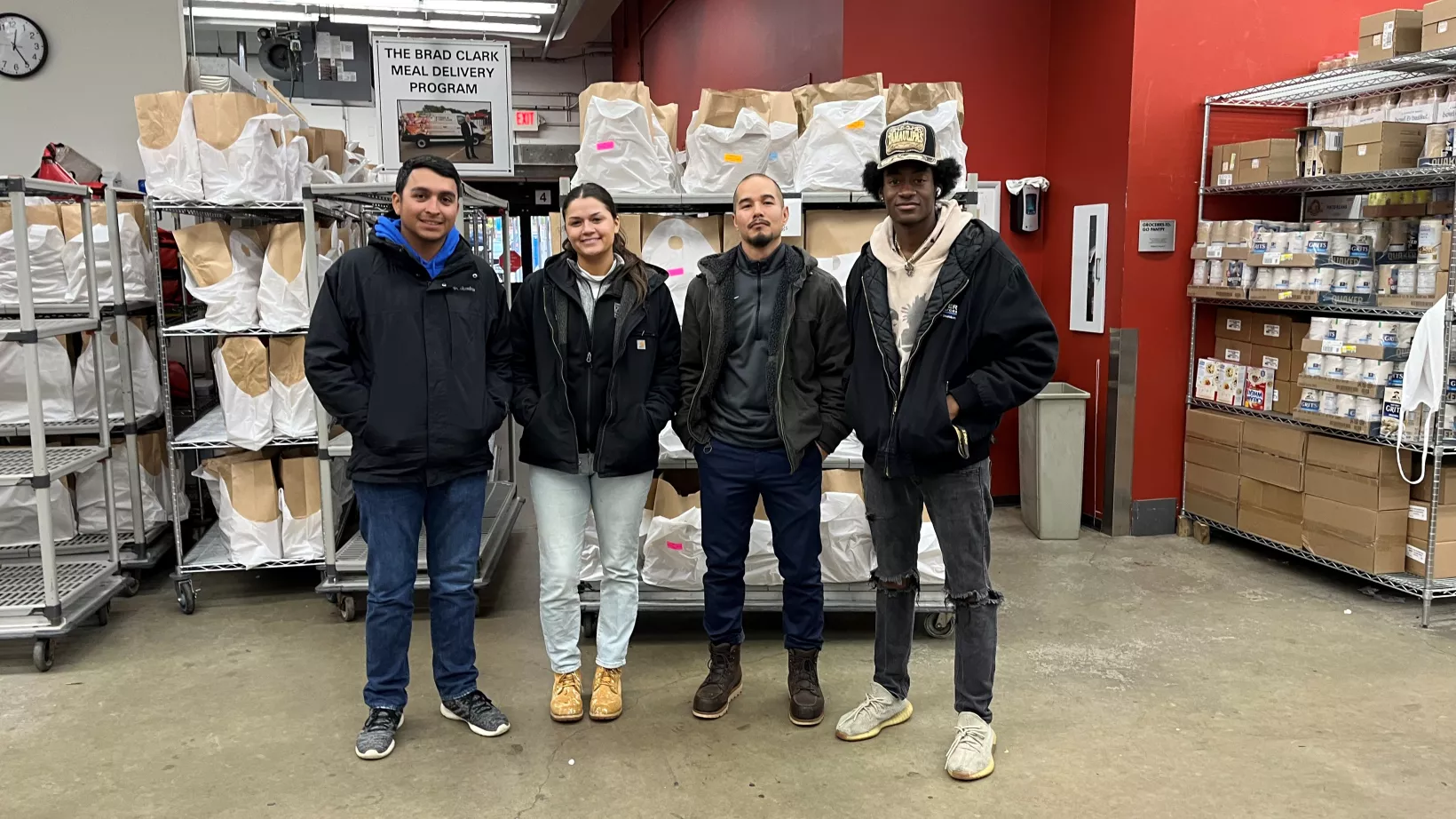 Four people pose in front of shelves of packaged food