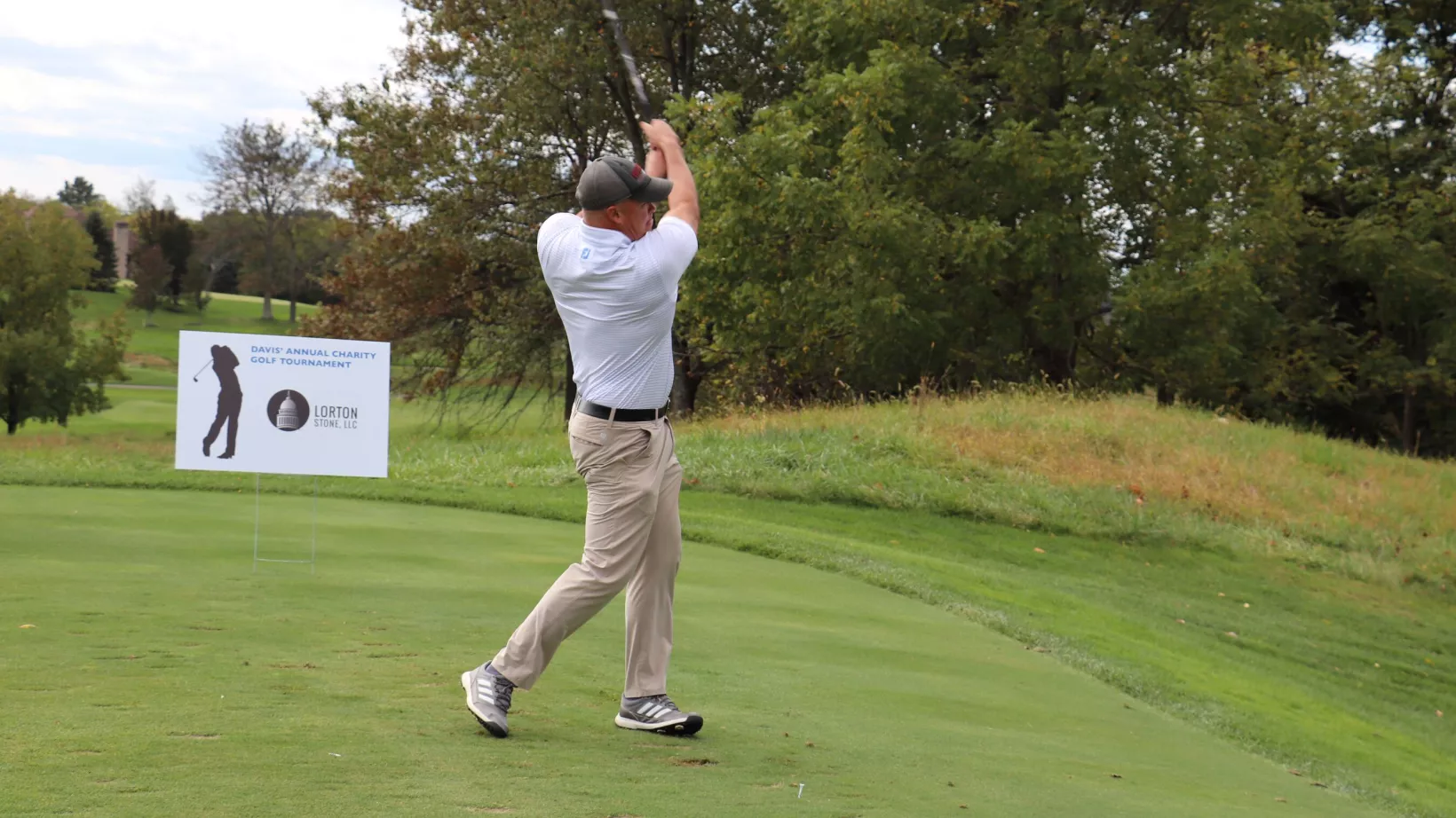 A man on the back end of his golf swing at the DAVIS Charity Golf Tournament