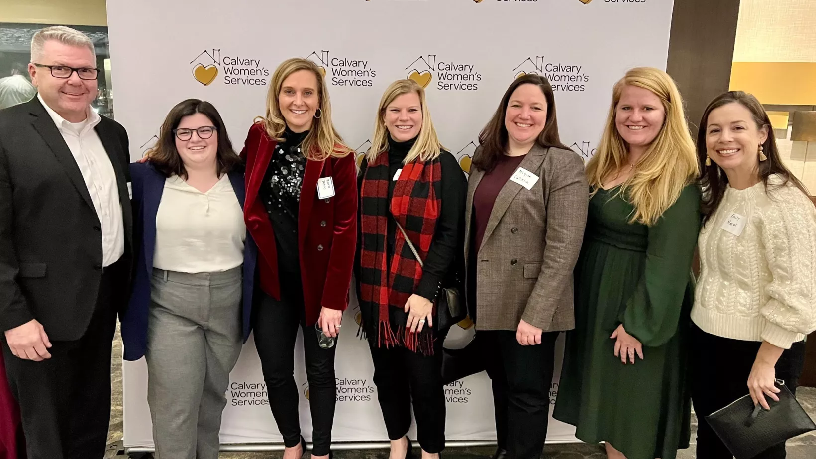 A group in front of a board with the Calvary Women's Services logo