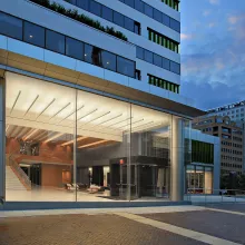 Exterior shot of a renovated building at night. The lobby of the building is lit up.