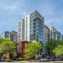 Exterior shot of an apartment building in the day. Trees are around.