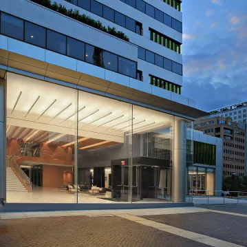 Exterior shot of a renovated building at night. The lobby of the building is lit up.