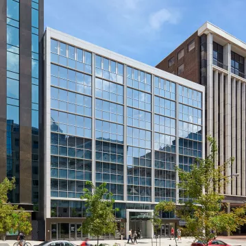 A glass office building on the side of a busy street.