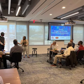 A man and a woman stand in front of an audience presenting minority business owners