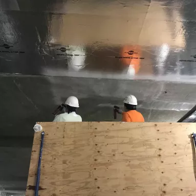 Two construction workers working on electromagnetic shielding on a project.