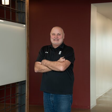 A man in professional wear stands in a hallway.