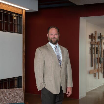 A man in professional wear stands in a hallway.