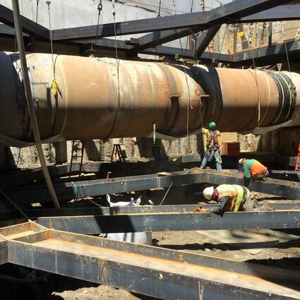 A group of construction workers near a large pipe structure