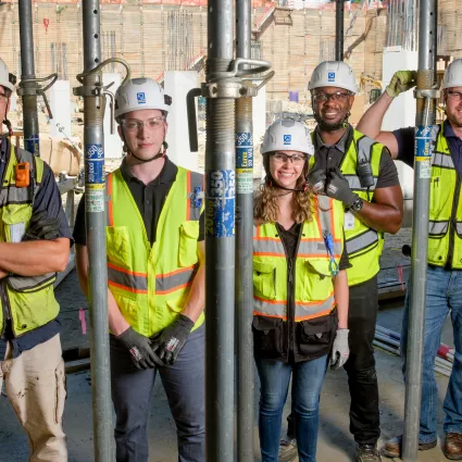 Five people in construction gear pose for a photo.