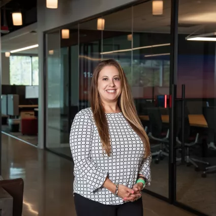 A woman in professional wear standing in an office hallway