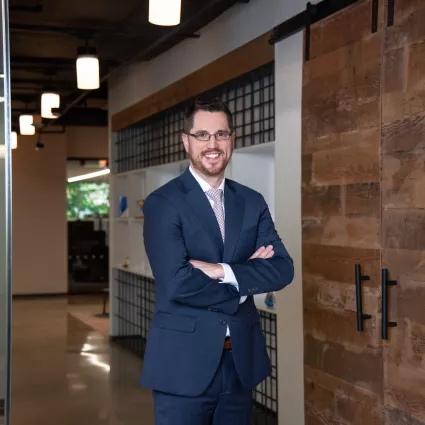 Man crossing arms in office hallway