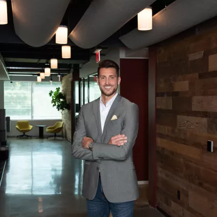 A man in professional wear stands in a hallway.