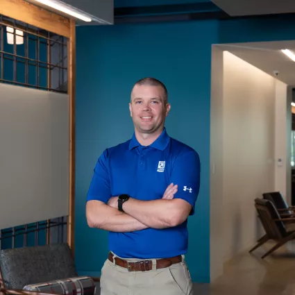 A man in professional wear stands in a hallway.