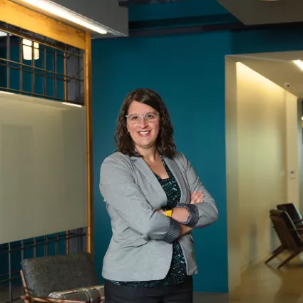 A woman in professional wear stands in a hallway.