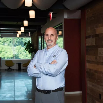 A man in professional wear stands in a hallway.