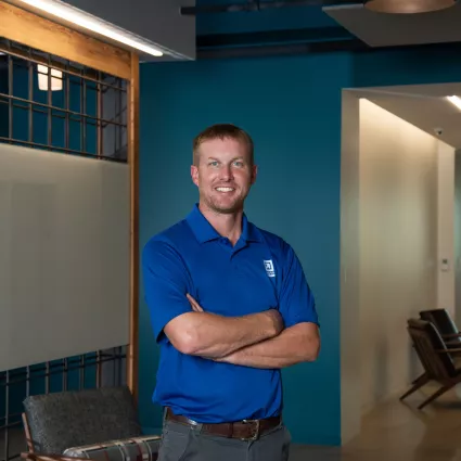 A man in professional wear stands in a hallway.