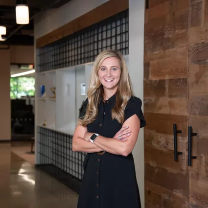 A woman in professional wear standing in an office hallway