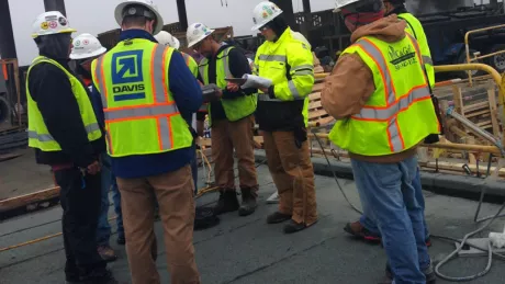 people in safety vests and hard hats in a huddle