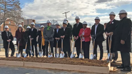 group of people in hard hats holding shovels at groundbreaking ceremony