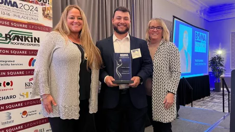 A man standing in between two women and holding an award