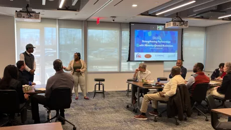 A man and a woman stand in front of an audience presenting minority business owners