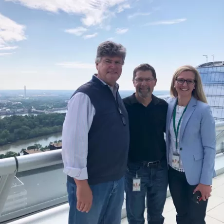 3 people standing on a rooftop with Washington Monument in background