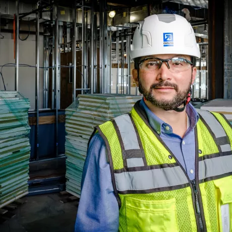 A man in construction gear stands in an ongoing project site.