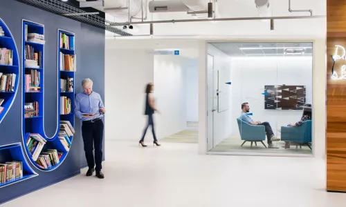 lobby area with bookcases on left and glass enclosed meeting room in the background