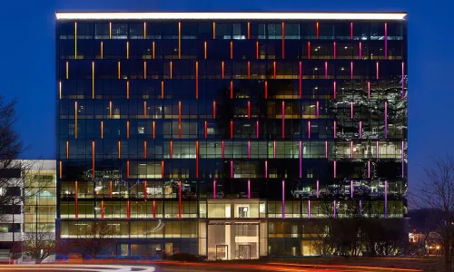 building at night with red and pink lights running vertical at one edge of every window