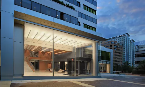 Exterior shot of a renovated building at night. The lobby of the building is lit up.