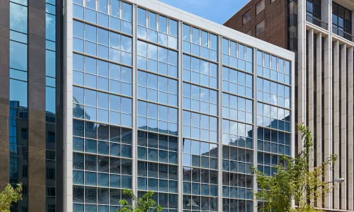 A glass office building on the side of a busy street.