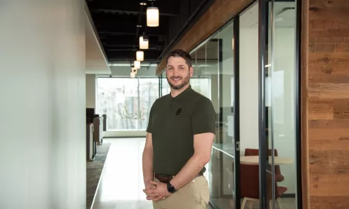 A man in professional wear stands in a hallway.