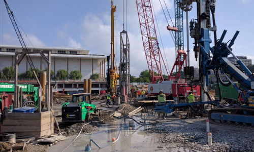 A group of construction workers on site with vehicles, materials, and debris around them.