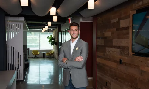 A man in professional wear stands in a hallway.