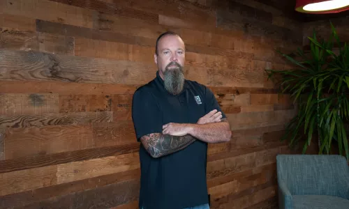 A man in professional wear stands in a hallway.