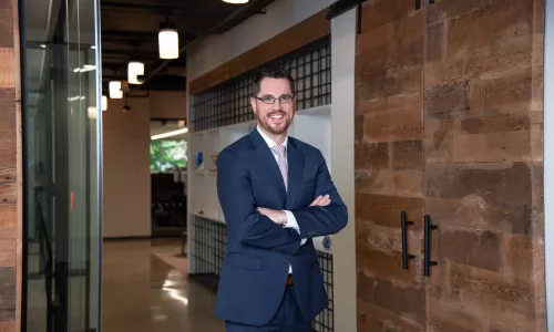 Man crossing arms in office hallway