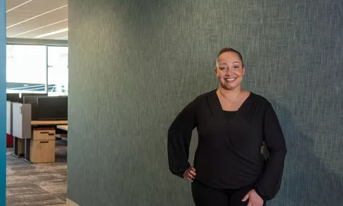 Woman in professional attire standing in front of green office wall