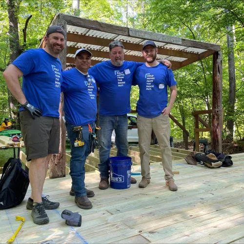 Four men pose in front of a community service project