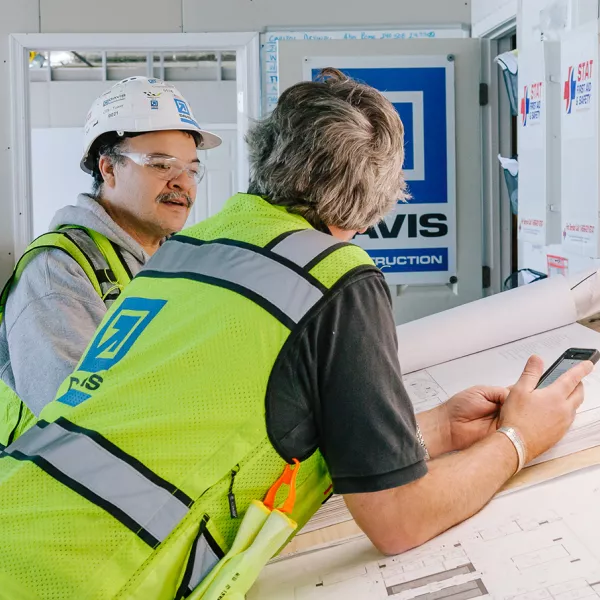 people in construction safety gear looking at construction plans