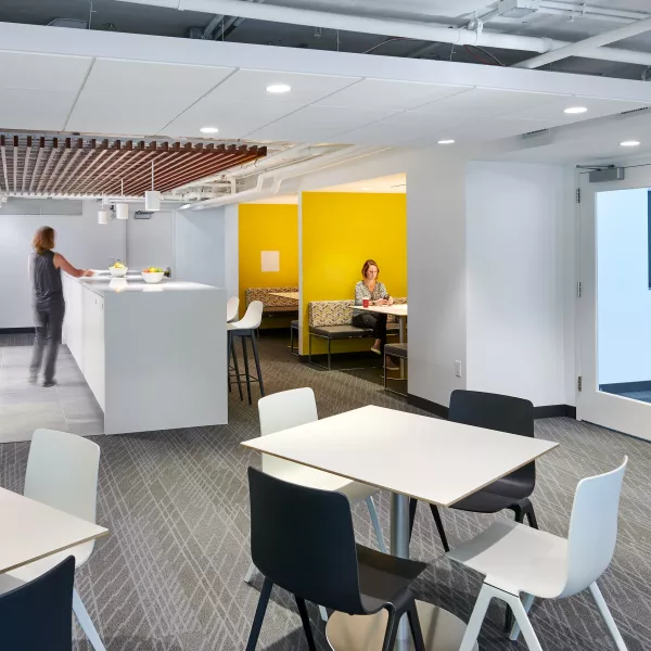 A common room with booths and tables as well as a kitchen.