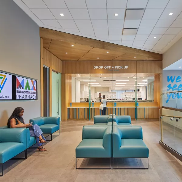 Patient sitting on couch in lobby in front of pharmacy