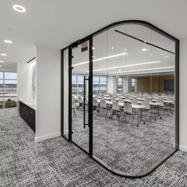 A conference room with glass doors and a gray carpet.