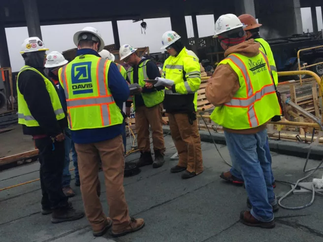 people in safety vests and hard hats in a huddle