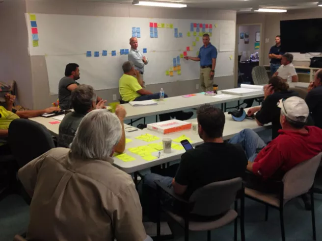 meeting with two people standing in front of a wall stickered with post-it notes