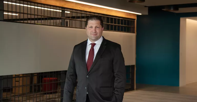 A man in professional wear stands in a hallway.